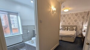 A hotel room with a bed, a bathroom, and a view of the outside. - The Walnut Tree Hotel (Bridgwater)