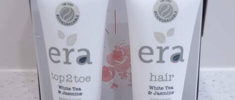 Two tubes of era hair conditioner and two tubes of era top 2 toe white tea & jasmine body wash on a countertop.