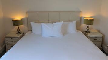 A neatly made bed with a headboard, two bedside tables with lamps, and a telephone on one of the tables.