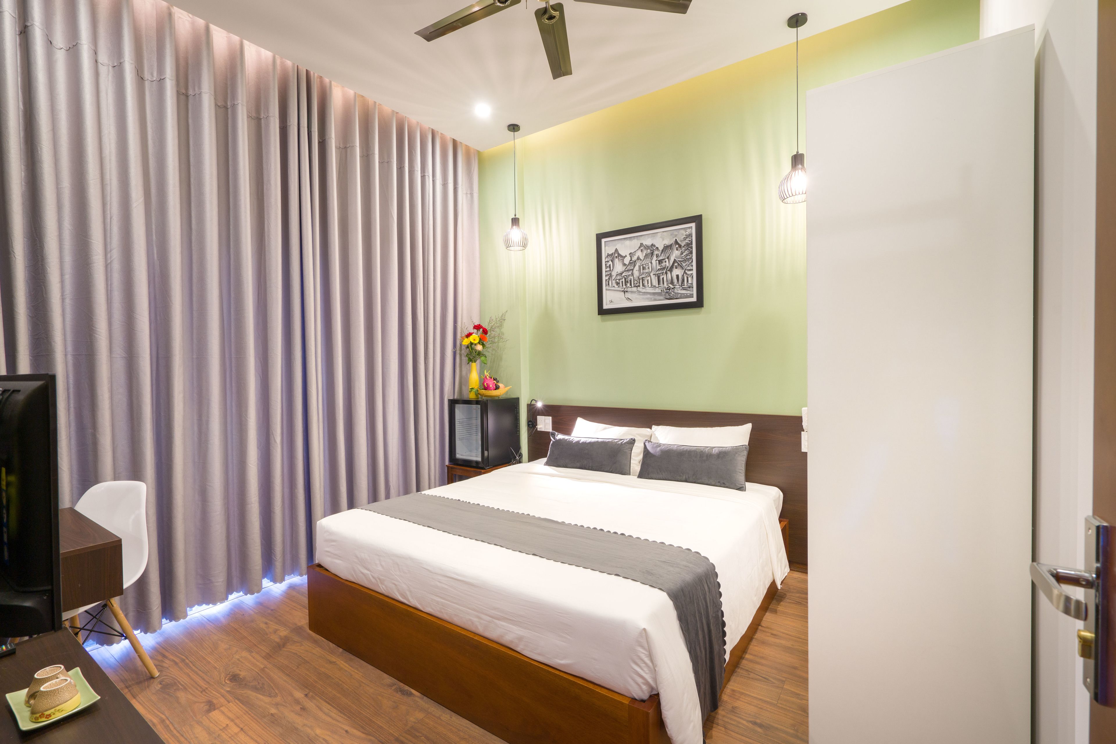 Une chambre d’hôtel moderne, dotée d’un grand lit, d’un bureau avec une chaise, d’une télévision et d’un tableau au mur.