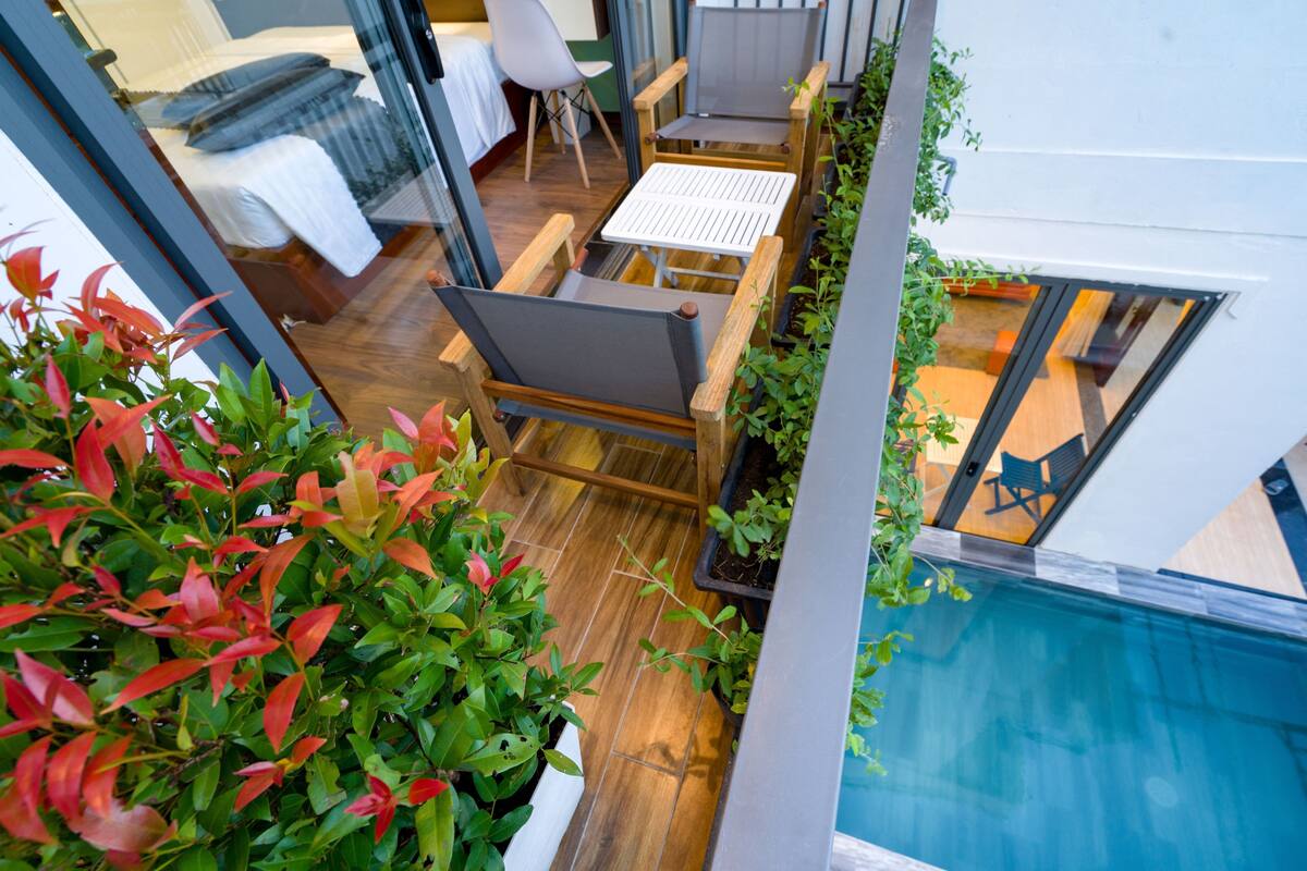 Ein modernes Interieur mit Holzboden, einem kleinen Tisch mit Stühlen und Blick auf einen Pool.