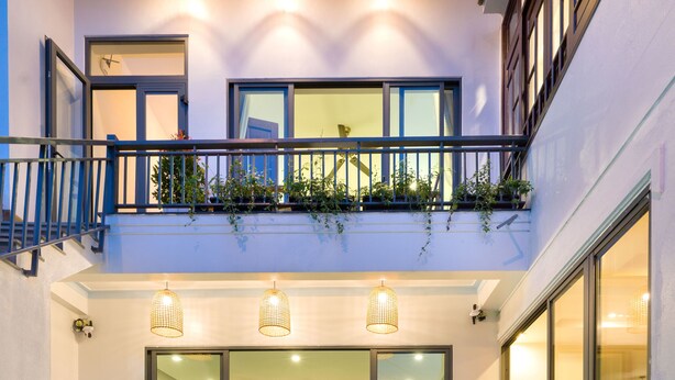 A modern indoor pool with clear glass walls, a balcony with plants, and a well-lit interior. - Le Printemps D' An Bang (Da Nang)