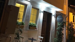 A two-story building with a sign for Yanki Hotel. There are potted plants on the ground floor and a table with chairs outside. - Yankı Hotel (Bursa)