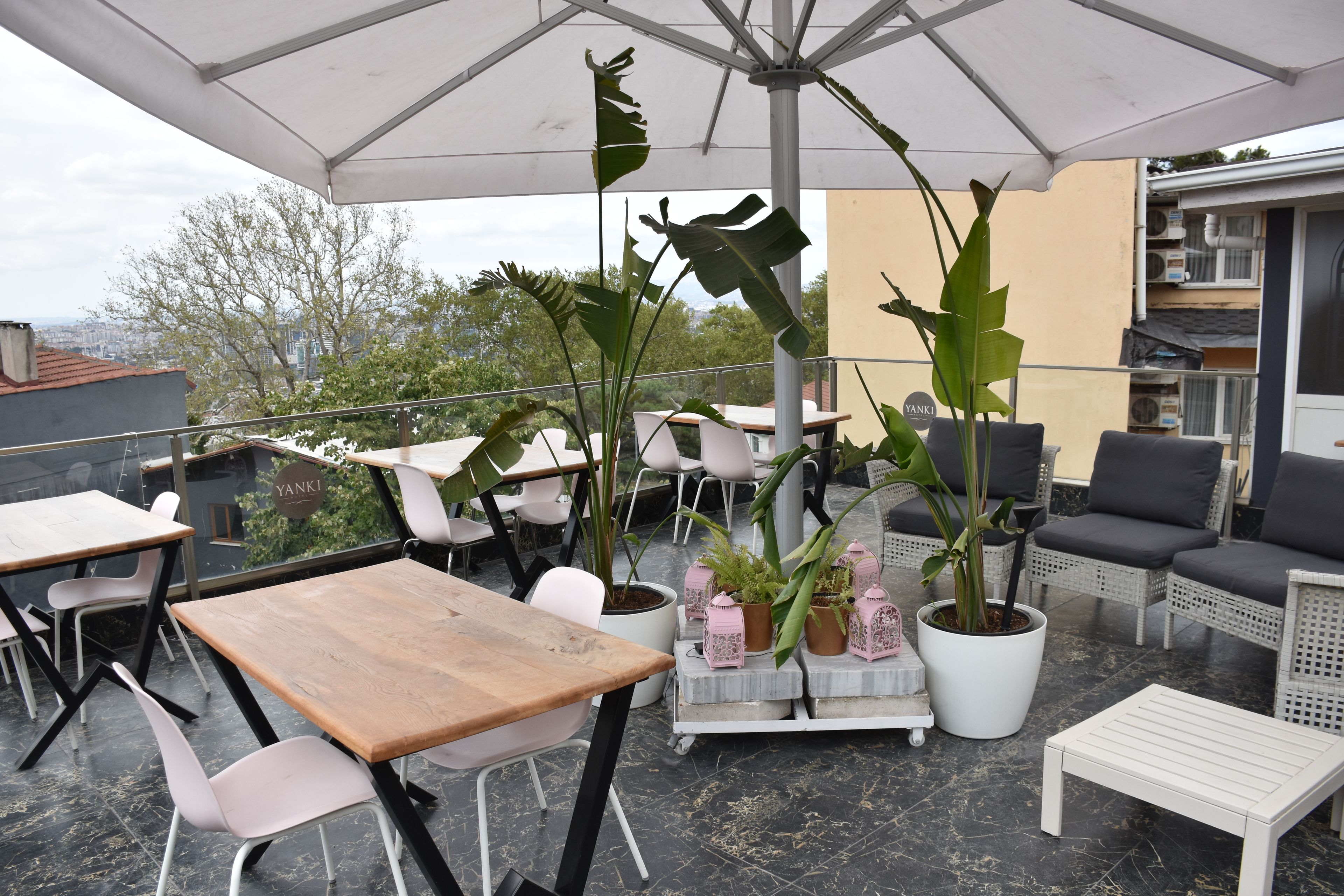 Un espacio al aire libre con mesas, sillas y plantas en macetas.