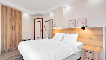 Un dormitorio moderno con una cama grande, un armario de madera, mesitas de noche y una obra de arte en la pared.