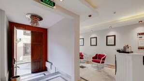 A hotel lobby with a reception desk, red chairs, framed artwork on the walls, and a patterned floor. - Yankı Hotel (Bursa)