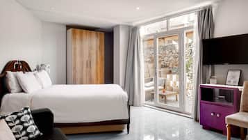 Un dormitorio moderno con una cama grande, un armario de madera, un televisor y vistas a una zona de estar exterior.