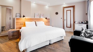 A hotel room with a large bed, wooden headboard, bedside tables, a desk with a chair, and a mirror. - Yankı Hotel (Bursa)