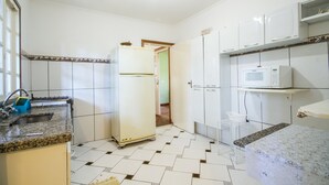 Uma cozinha com armários brancos, micro-ondas, geladeira e pia com torneira.