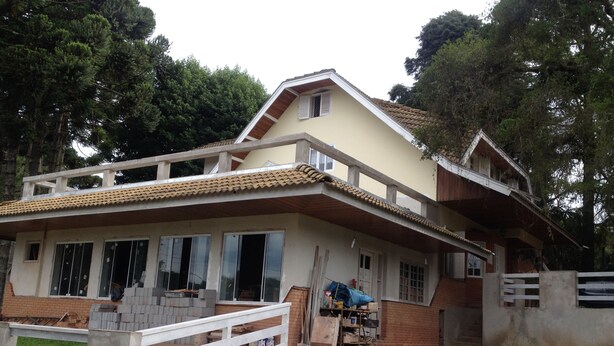 Uma casa de dois andares com varanda, alpendre e um pequeno jardim.