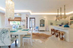 Une cuisine moderne avec un plan de travail blanc, des luminaires suspendus et un meuble vitré.