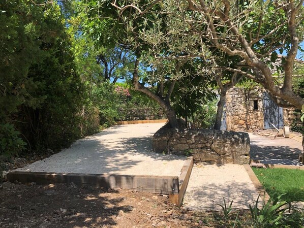 Un sendero de grava que conduce a un edificio de piedra, rodeado de follaje denso y un pequeño jard ín.