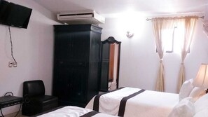 A hotel room with two beds, a wardrobe, a TV, and an air conditioning unit. - Hotel Hacienda Los Narcisos (San Juan de los Lagos)