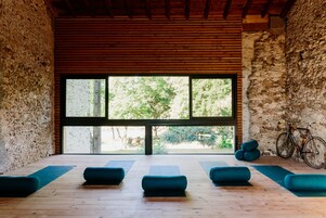 Una habitación con un ventanal grande, piso de madera y asientos con cojines azules.
