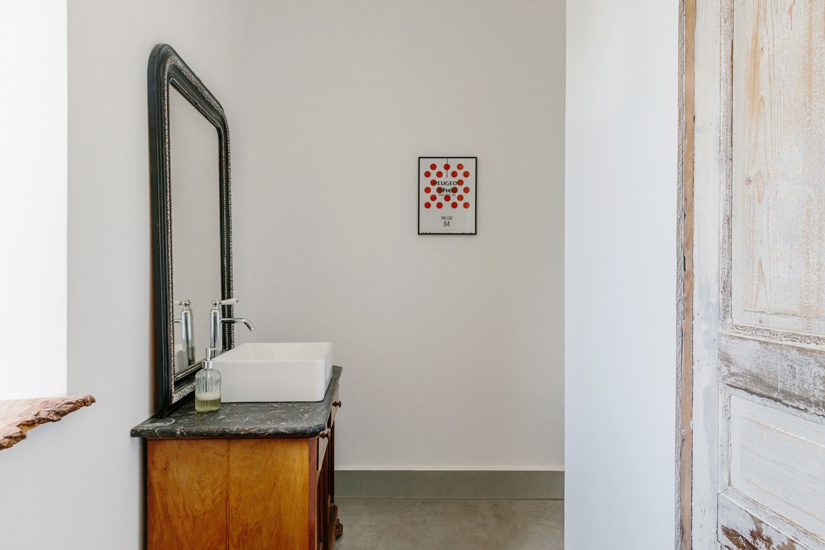 A bathroom with a white sink, a mirror, and a framed picture on the wall.