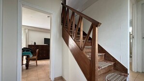 A wooden staircase with a handrail, leading to a landing with a patterned rug. - Quiet 4-room house, near St Colomban beach, pets allowed (Carnac)