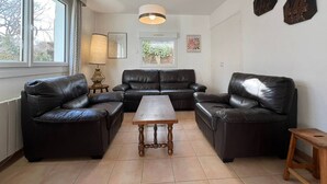 A living room with a sofa set, a wooden coffee table, a lamp, and a window with curtains. - Quiet 4-room house, near St Colomban beach, pets allowed (Carnac)