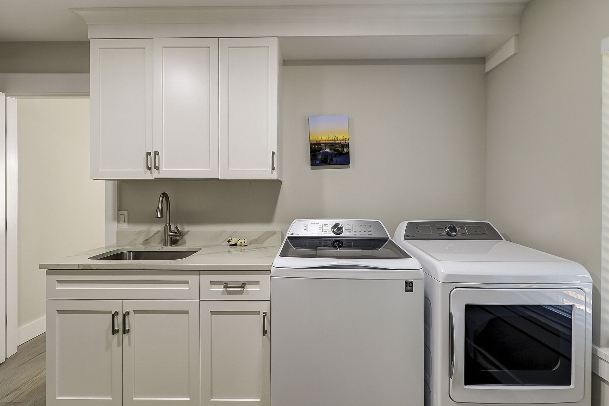 Une cuisine compacte avec des meubles blancs, un évier, ainsi qu’un lave-linge et un sèche-linge à chargement frontal.