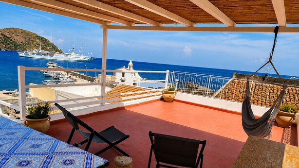 A terrace with a view of the sea, a hammock, and a table with chairs. - Casa Giuliana (Lipari)