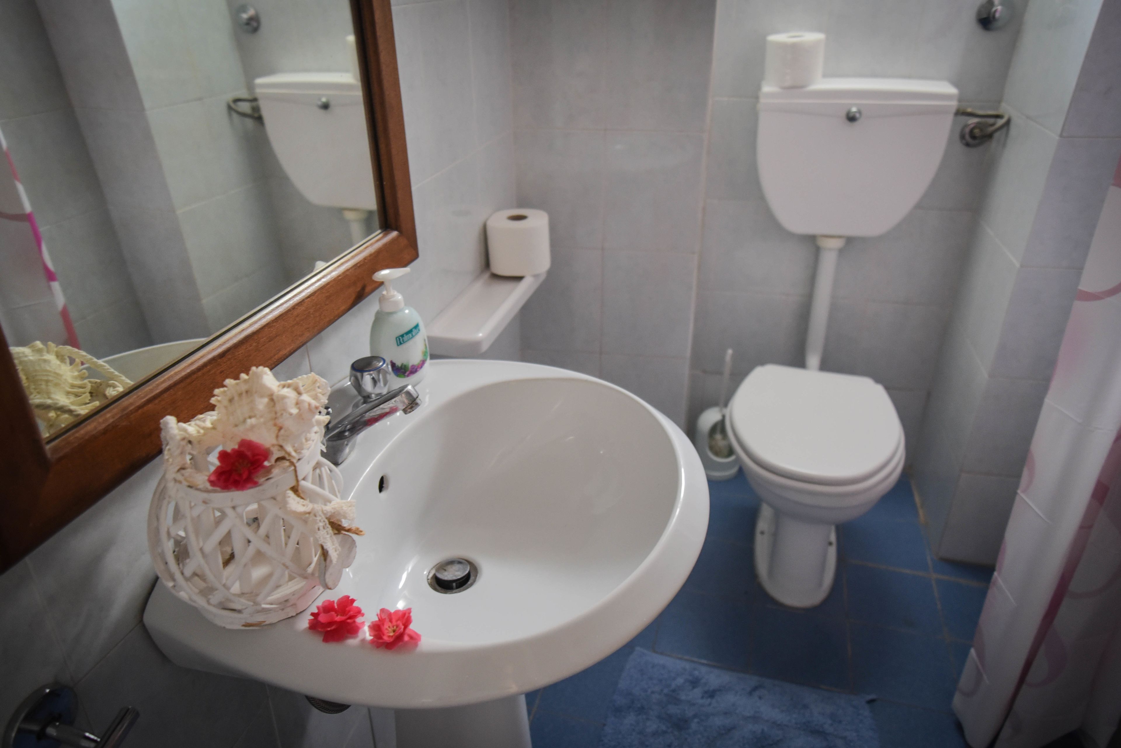Un bagno con un lavandino bianco, il water e piastrelle blu sul pavimento.