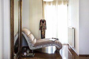 A corner room with a sofa, a mirror, a radiator, and a window with curtains.