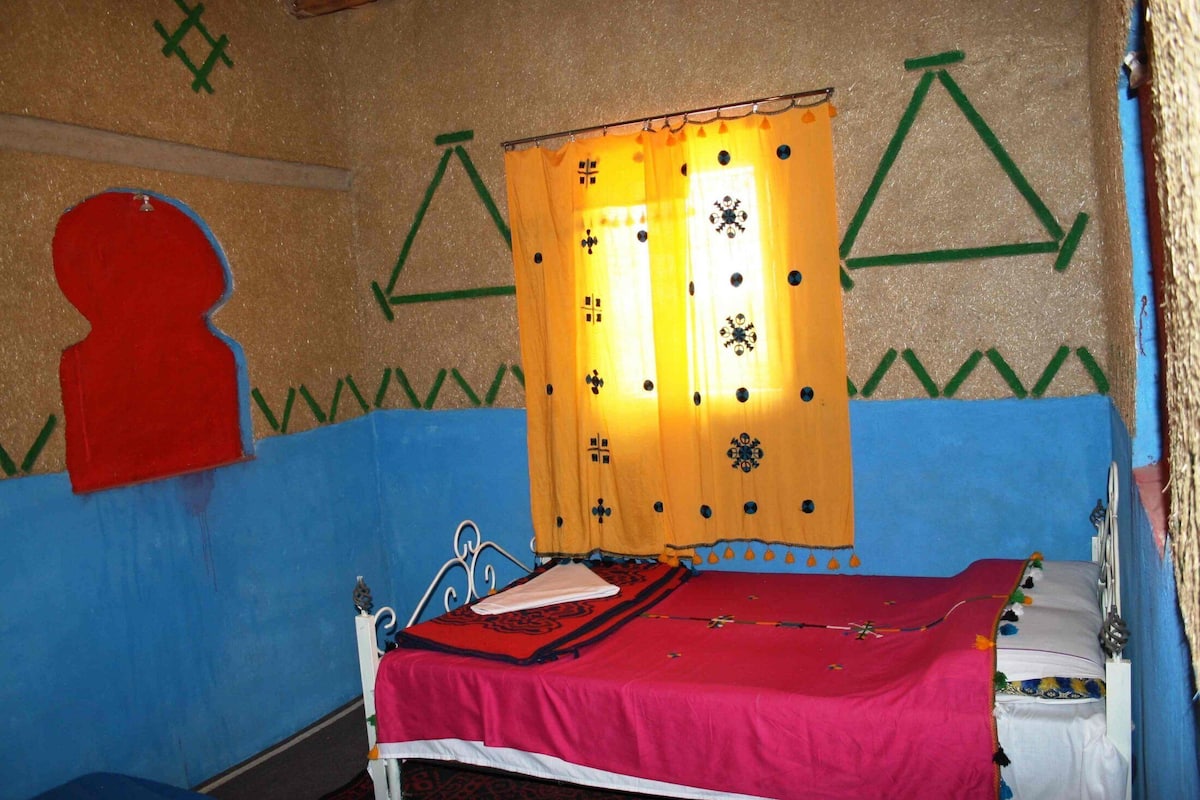 Una habitación con una cama, un adorno silueta roja y diseños geométricos en la pared.
