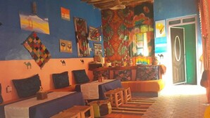 A room with a long sofa, a small table, and a patterned rug. - Kasbah Casa Khamlia (Taouz)