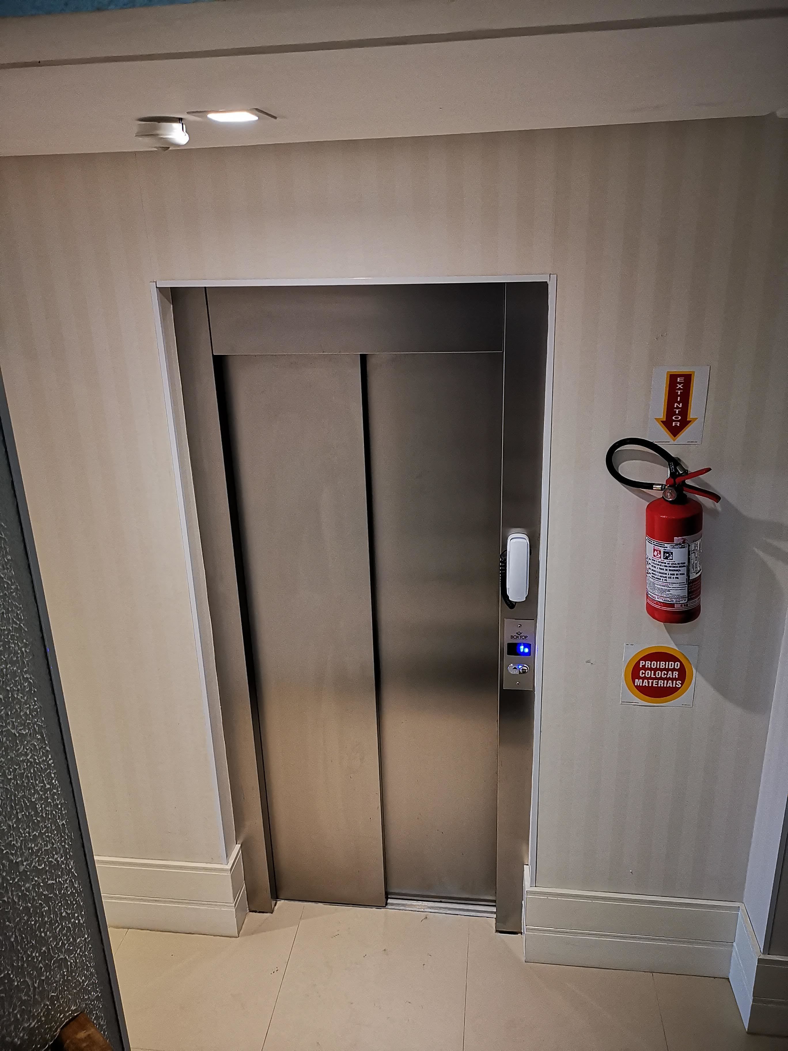 An elevator with a fire extinguisher and a sign indicating it's prohibited to store materials.