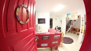 A red reception desk with stickers, a spiral decoration, and a staircase in the background. - Inefável Hostel Floripa (Florianópolis)