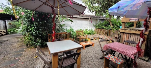 An outdoor patio with a table and chairs, surrounded by a wooden fence and greenery.
