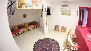 A room with a wooden bench, a colorful rug, and a red table with chairs. - Inefável Hostel Floripa (Florianópolis)