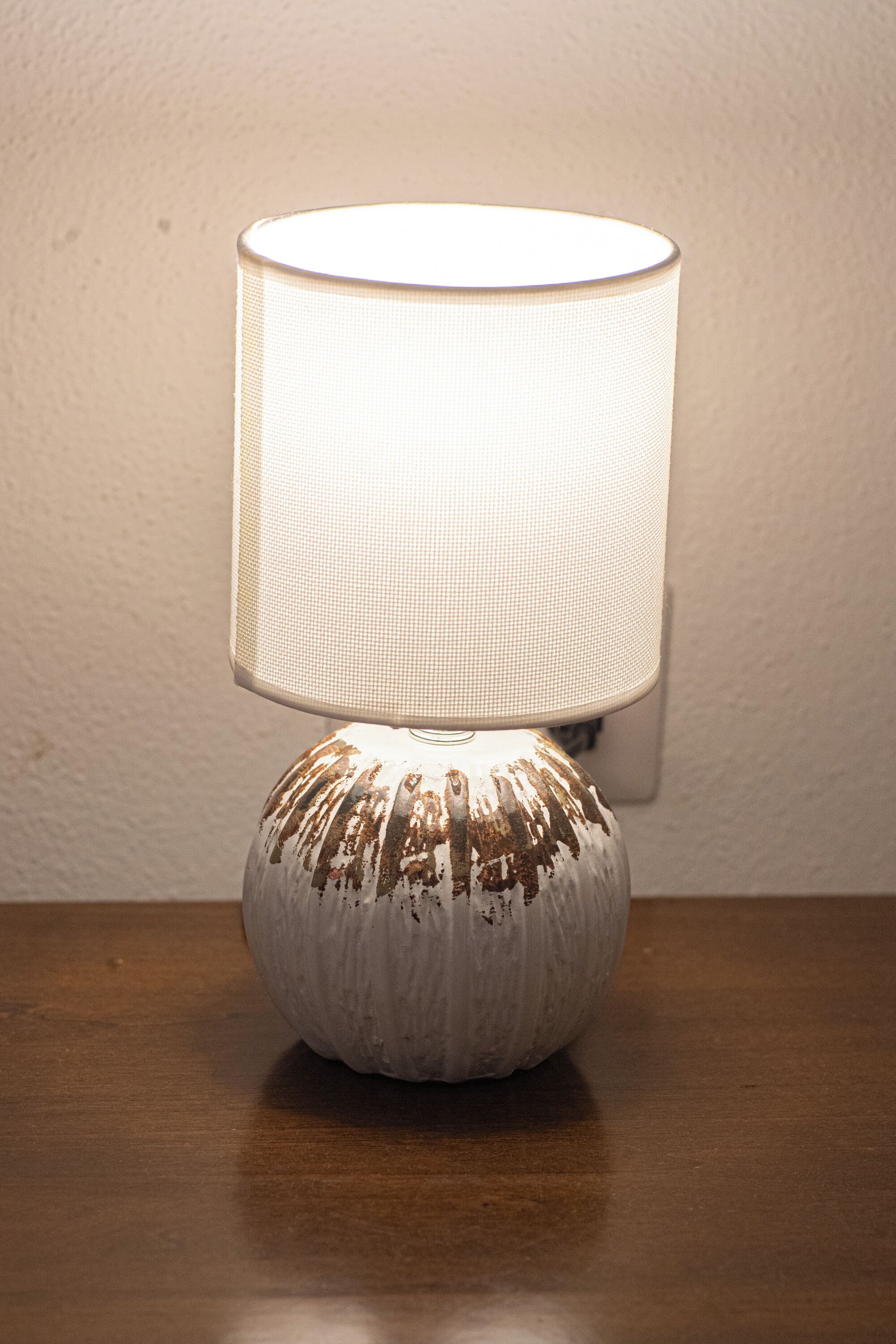 A table lamp with a textured base and a white lampshade.