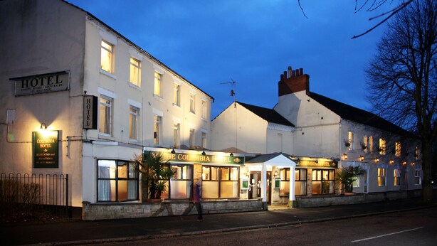 A hotel with multiple units, a signboard, and a well-lit entrance. - Columbia Hotel & Restaurant (Wellingborough)
