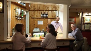A bar area with wooden paneling, a cash register, and bottles of wine. - Columbia Hotel & Restaurant (Wellingborough)