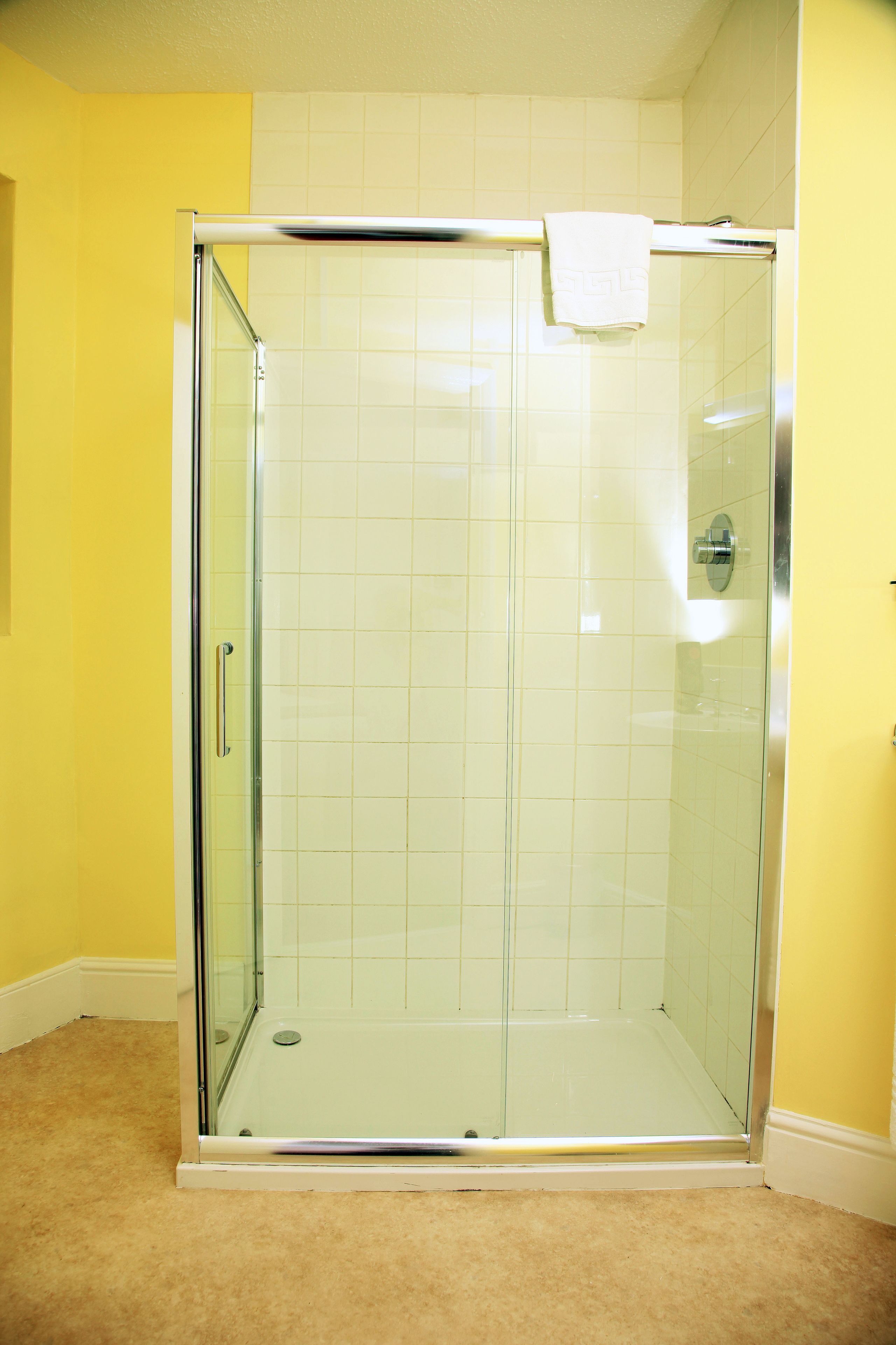 A glass-enclosed shower with a white towel hanging on the door handle.