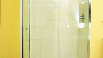 A glass-enclosed shower with a white towel hanging on the door handle.
