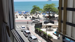 Vista desde una ventana que da a una calle concurrida, con coches, una zona peatonal y un gran crucero en la distancia.