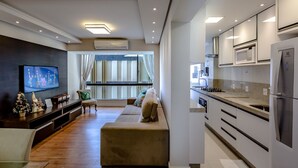 Una cocina moderna con electrodomésticos integrados y un comedor con sofá y televisor.
