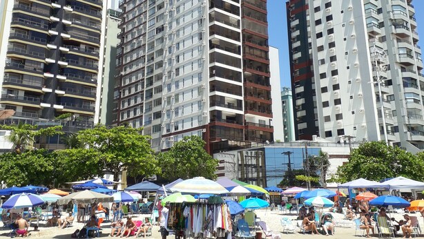 Zona urbana junto a la playa con edificios altos, sombrillas y gente relajándose.