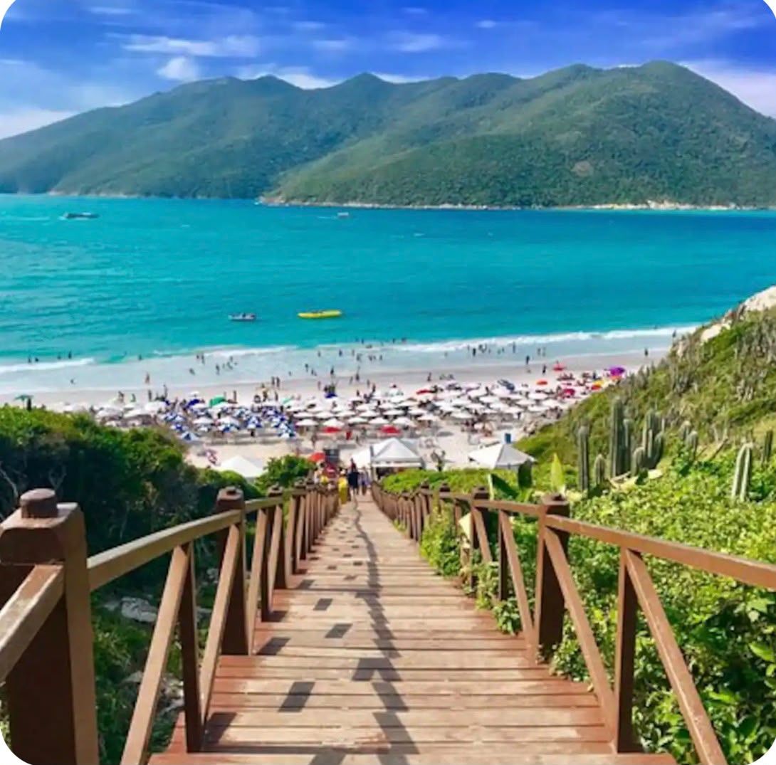 Un escalier en bois menant à une plage où se trouvent des parasols et des gens.