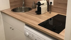 Una cocina compacta con cubierta de madera, un lavamanos, horno integrado y lavavajillas.