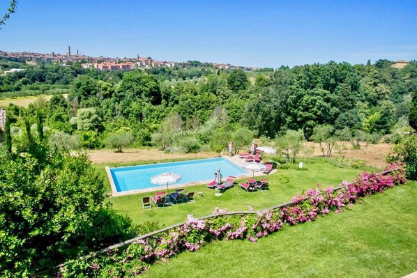 A swimming pool with lounge chairs and a view of a cityscape in the background.