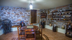 A stone-walled room with a wooden dining table and chairs, a chessboard, and a wine rack against the wall. - Cabanelas Country House Casa do Afonso (Vale de Cambra)