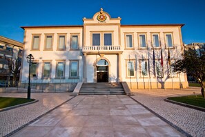 Un bâtiment à la façade symétrique, doté d’une entrée centrale avec des marches et d’un balcon au-dessus de la porte.