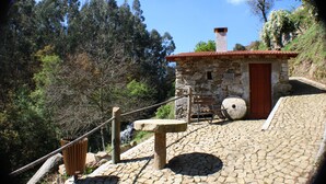A stone building with a red-tiled roof, a wooden door, and a stone bench. - Cabanelas Country House Casa do Afonso (Vale de Cambra)
