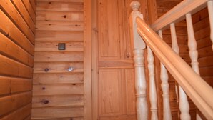 A wooden staircase with a handrail and a door with a small light fixture.