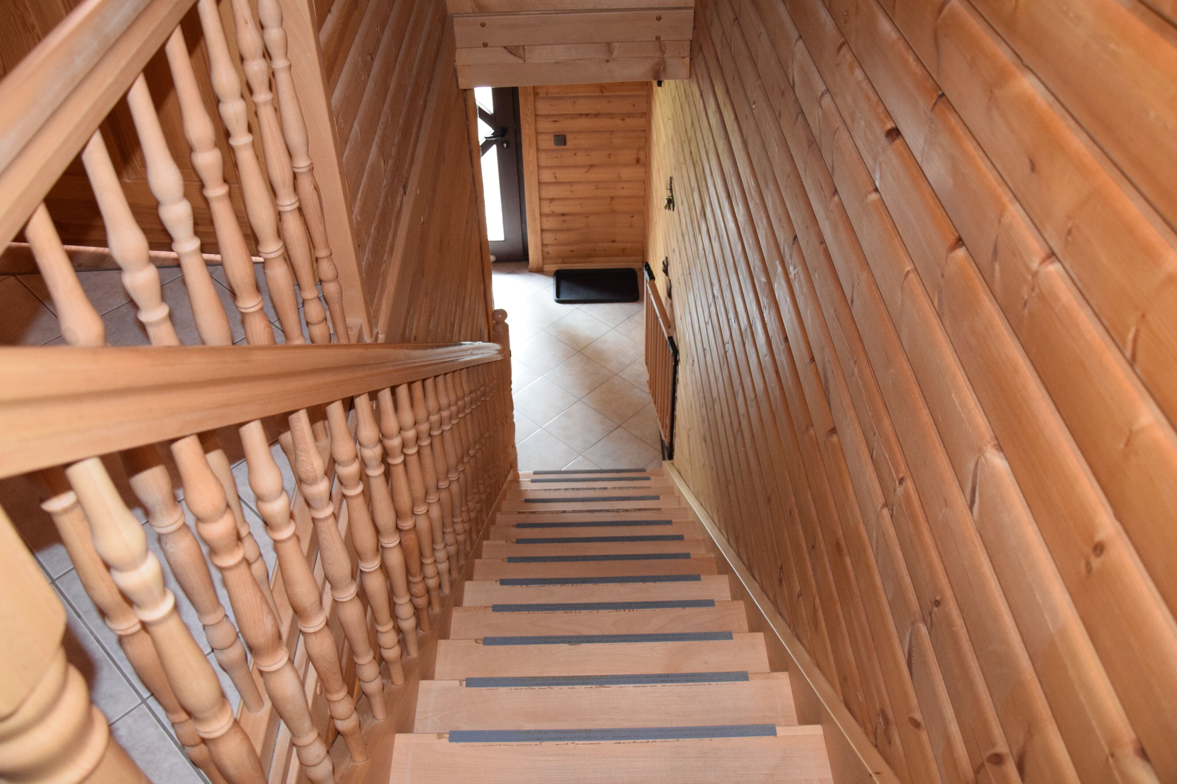 Eine Holztreppe mit Handlauf, die zu einem Raum mit Holzwänden und einer Tür führt.