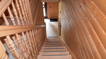 Eine Holztreppe mit Handlauf, die zu einem Raum mit Holzwänden und einer Tür führt.