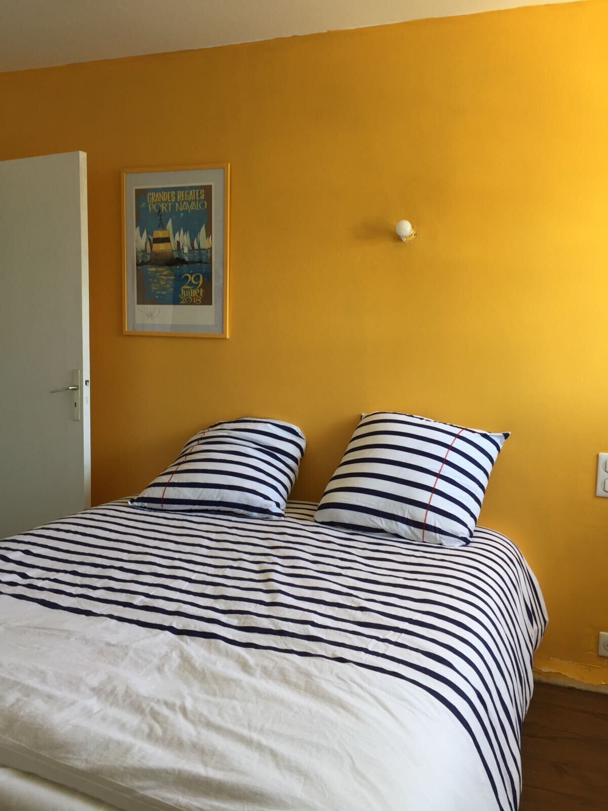 A bed with striped bedding in a room with yellow walls.