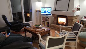 Un salon chaleureux avec une cheminée, des fauteuils confortables et un téléviseur.